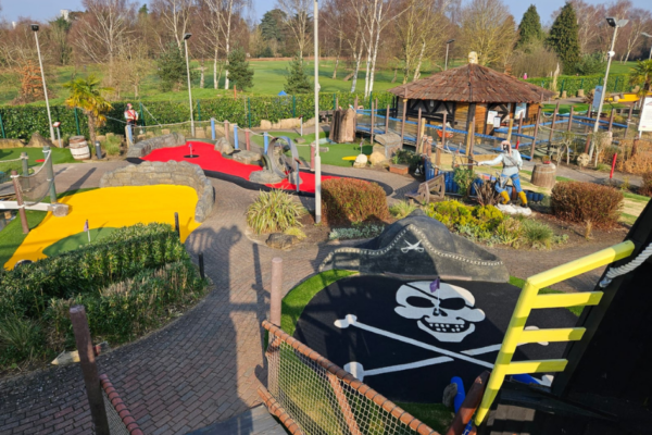 Adventure Golf Resurfacing with Artificial Grass. adventure golf, crazy golf, mini golf venue. colourful artificial grass. putting. skull and bones. pirate themed. A colourful adventure golf course at Hoebridge Golf Centre featuring artificial grass in various vibrant colours including yellow, red, and black with a pirate theme.